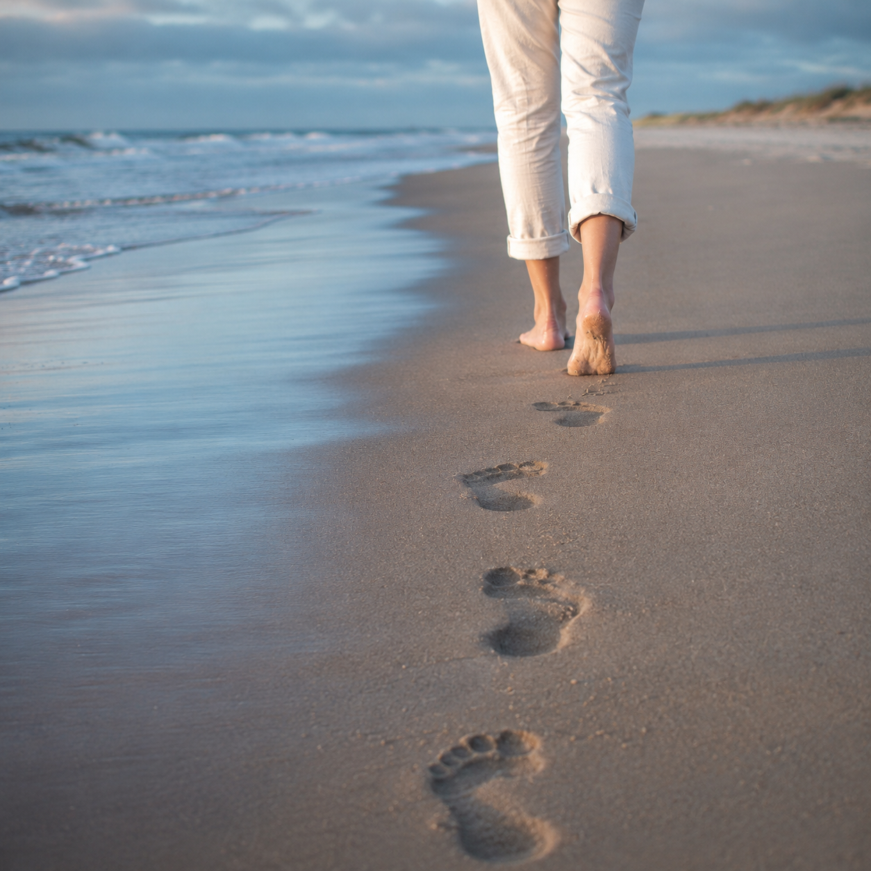 Picture of a woman leaving footprints in the sand on the beach in Fernandina Beach, FL