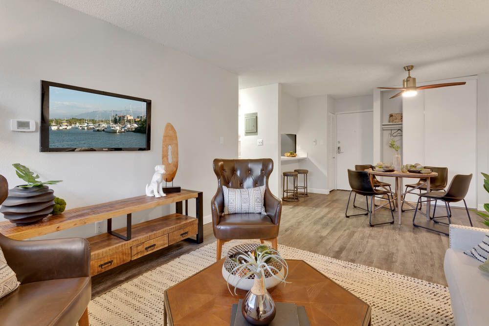 Bright open living room with wood console, wall art, woven rug, and dining area in the background