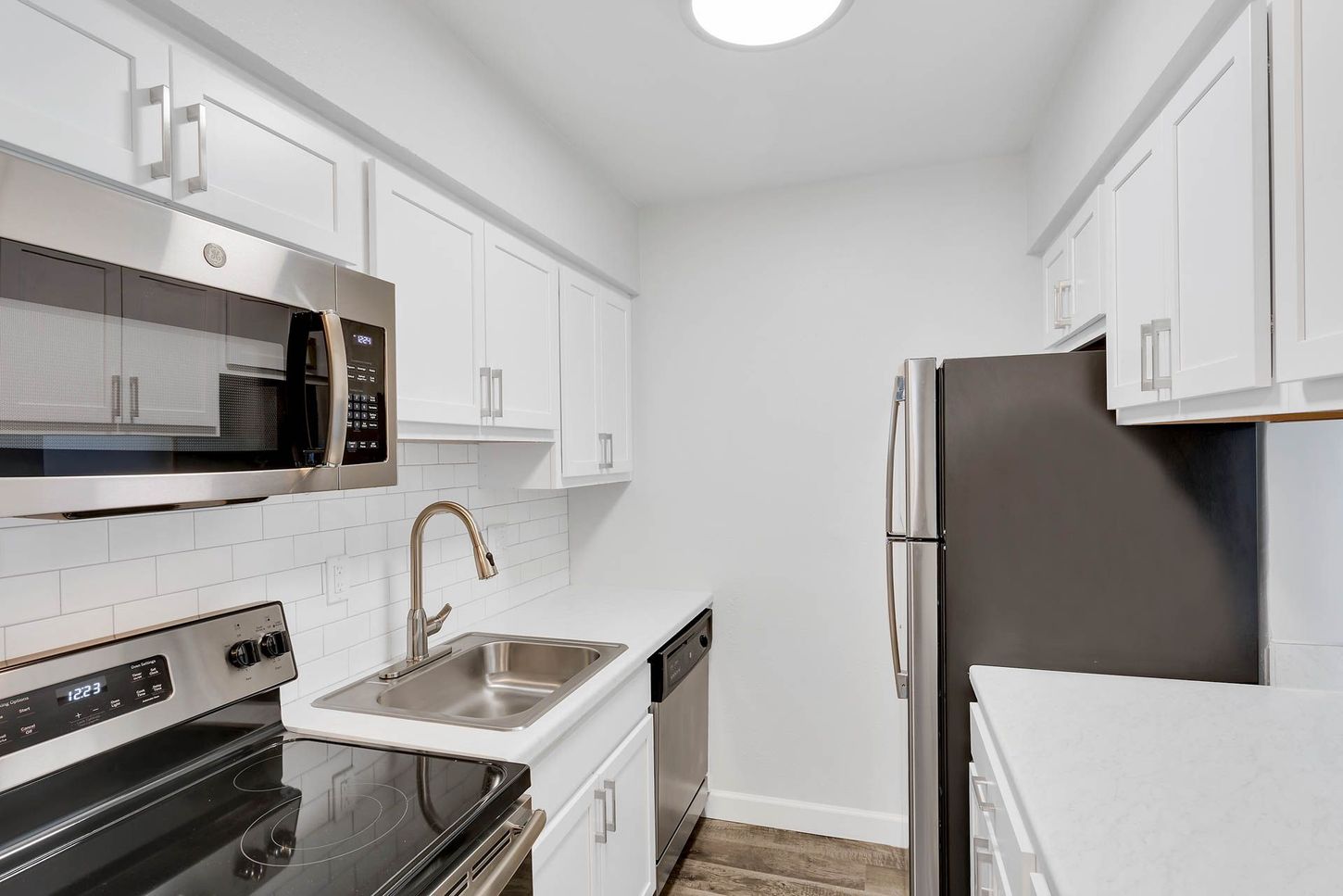 Bright white galley kitchen with stainless steel appliances and granite counters