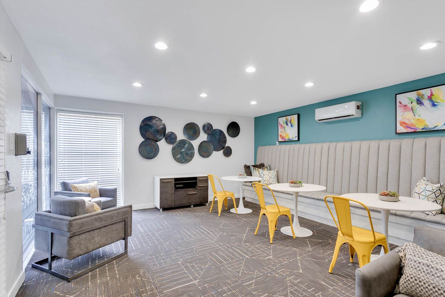 Bright kids’ classroom with white tables, yellow chairs, gray decor, and colorful wall art