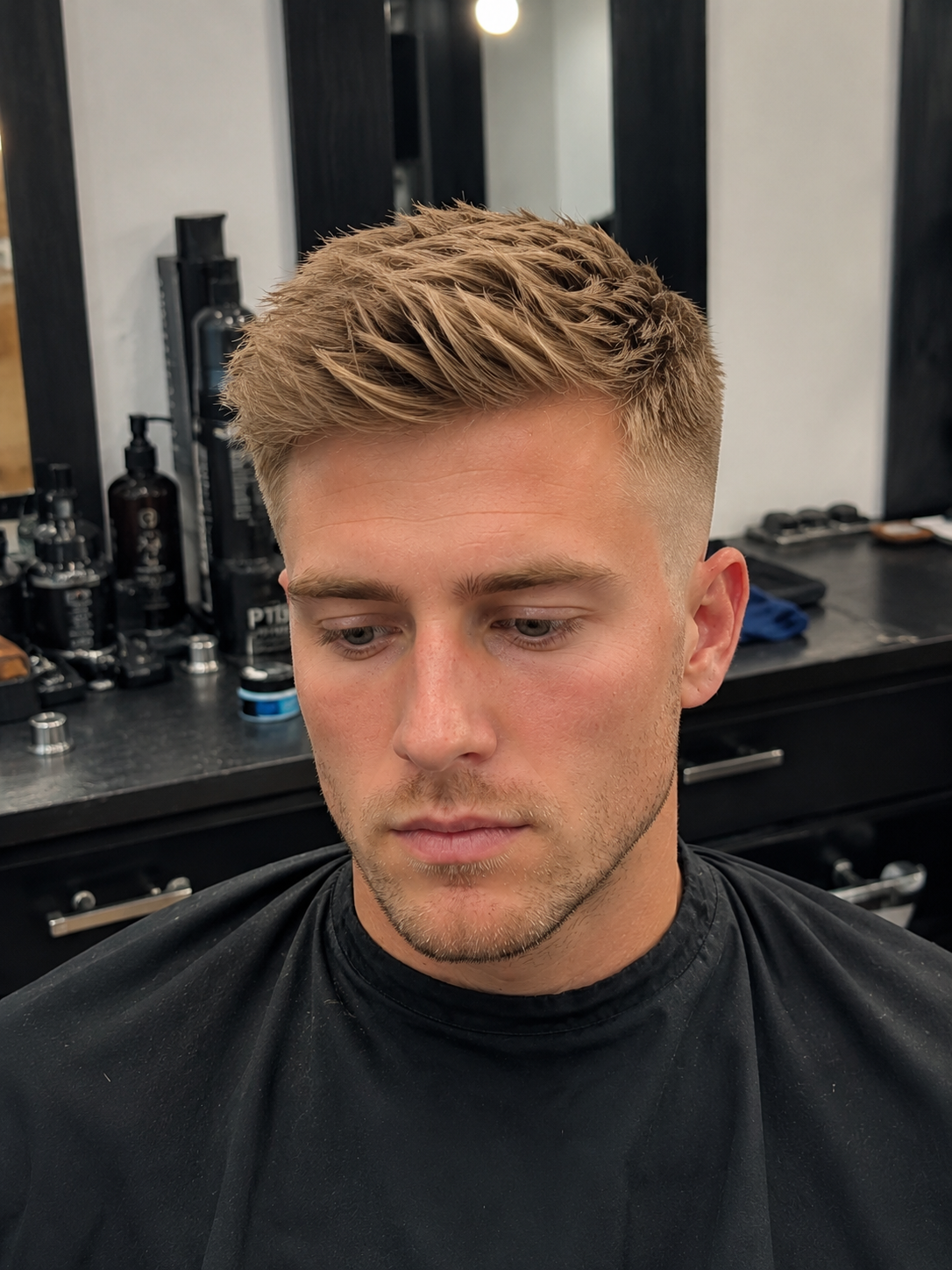 Young male client with a modern quiff haircut featuring textured volume on top and a clean fade.