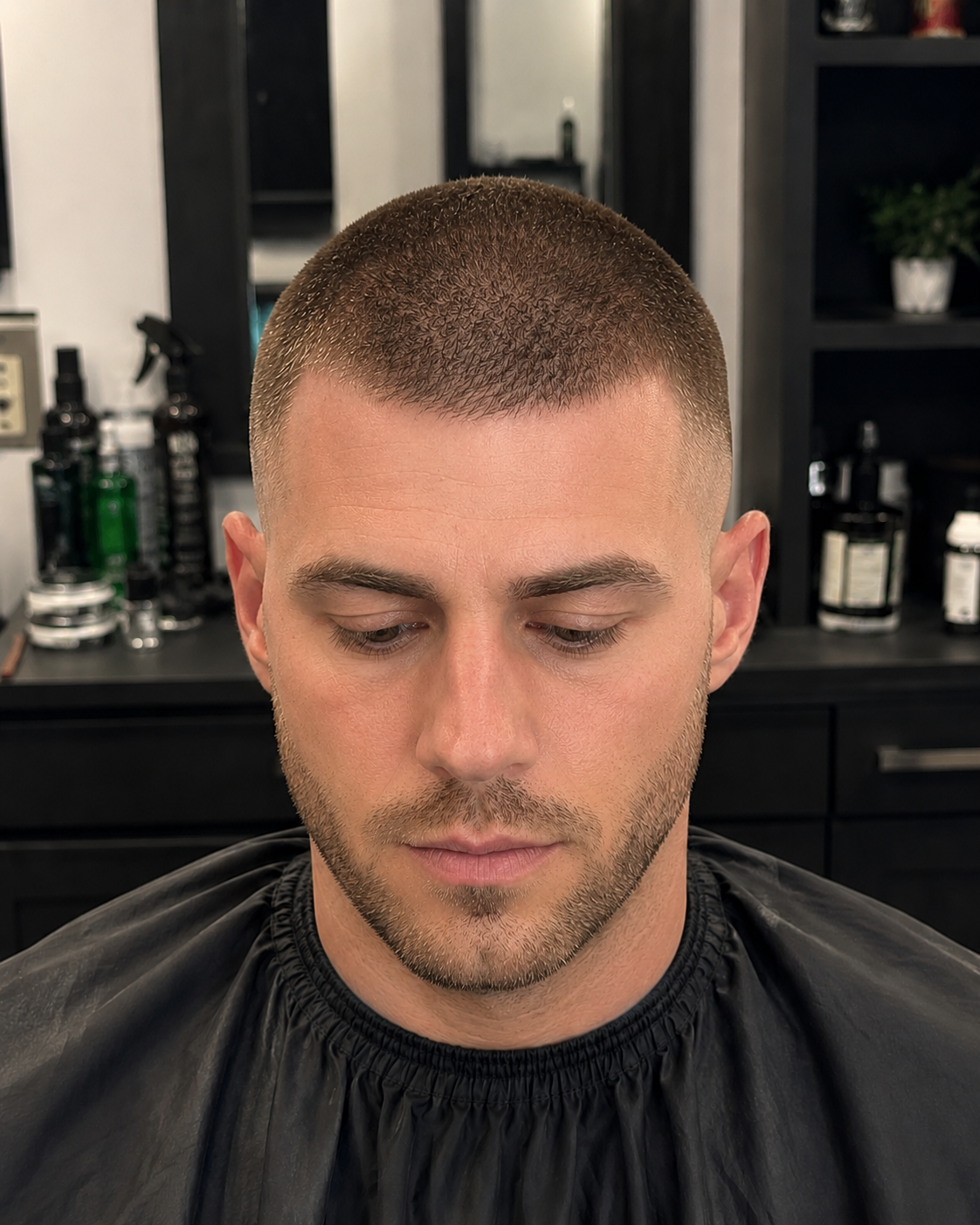 Adult male client with a clean buzz cut showcasing a sharp low-maintenance men's haircut in a professional barbershop.