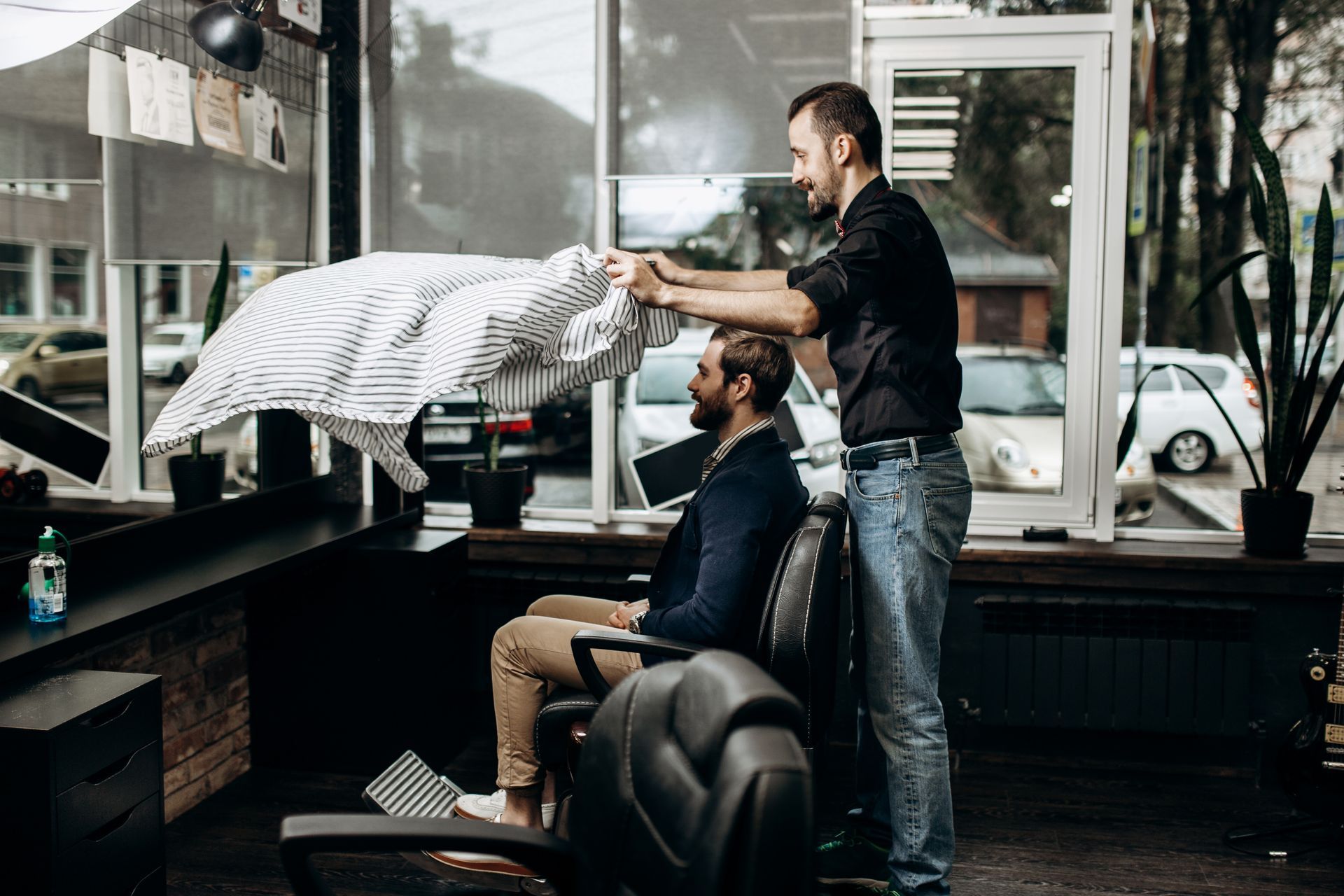 Barber placing a cape on a client before a men’s haircut consultation in a barbershop