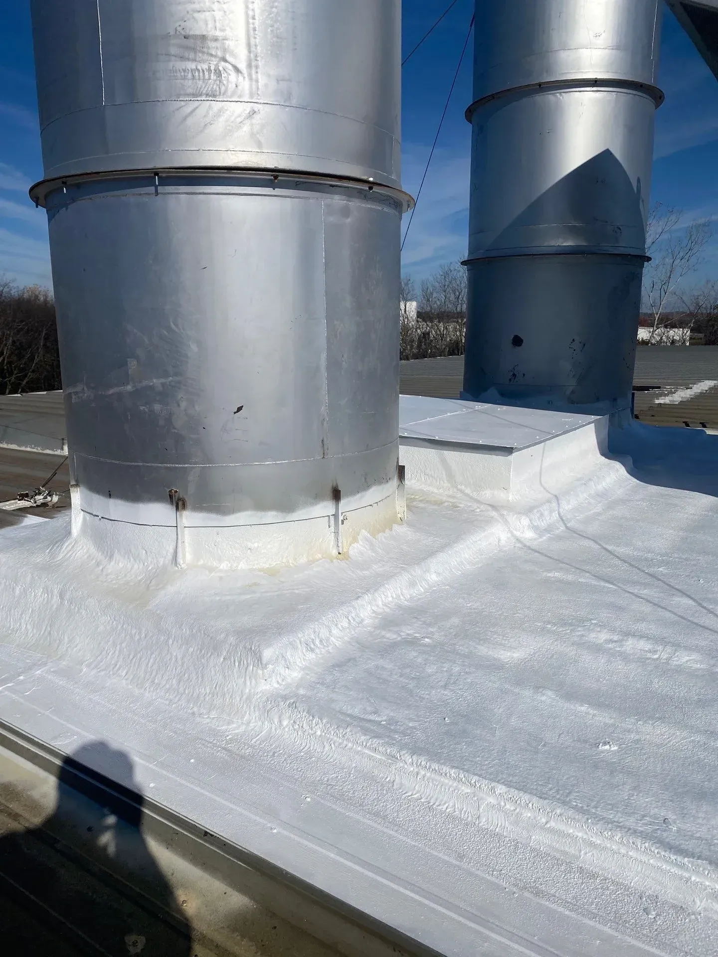 Sealed rooftop exhaust stack penetrations with white SPF foam and reflective coating after restoration in Clarksville, Tennessee