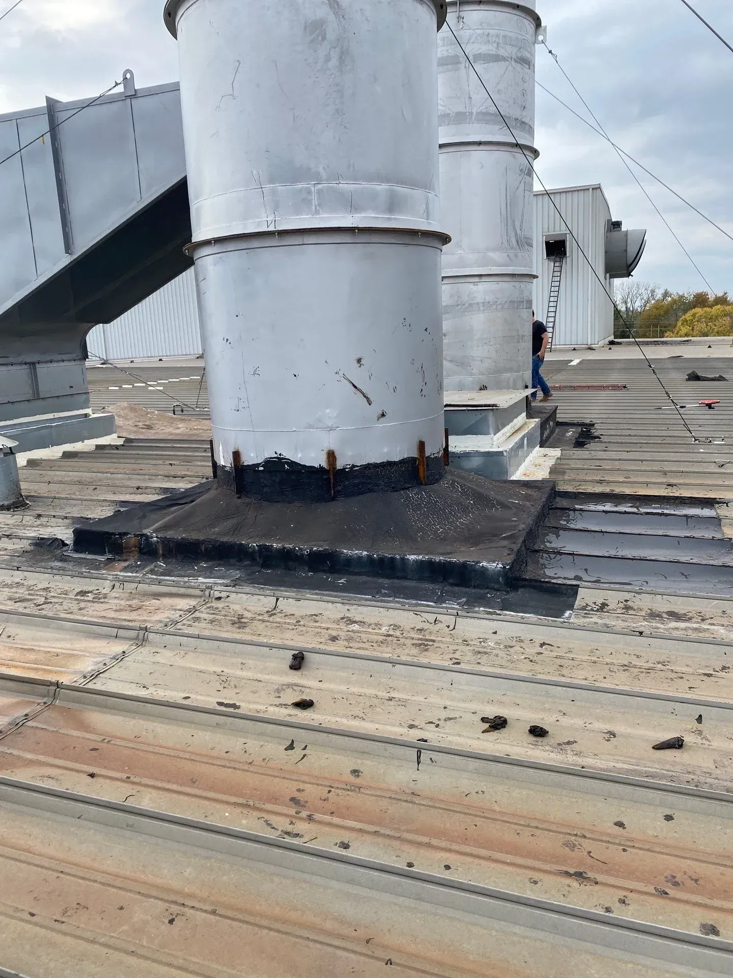 Deteriorated black flashing and rusted metal roof panels around rooftop exhaust stacks before restoration in Clarksville, Tennessee