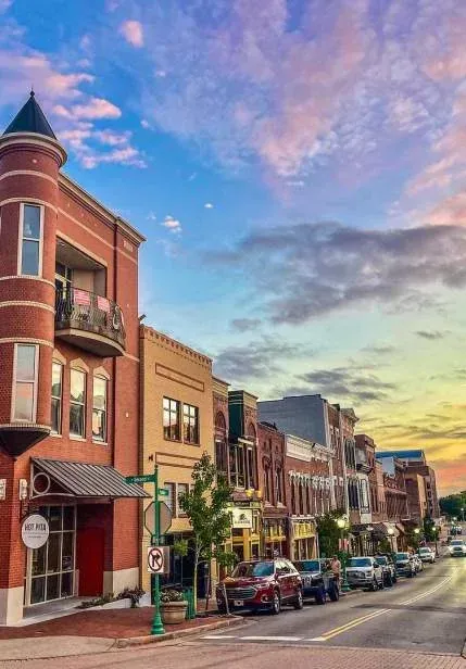 Historic downtown Main Street in Clarksville, Tennessee at sunset, with a turreted brick corner building and storefronts along the street
