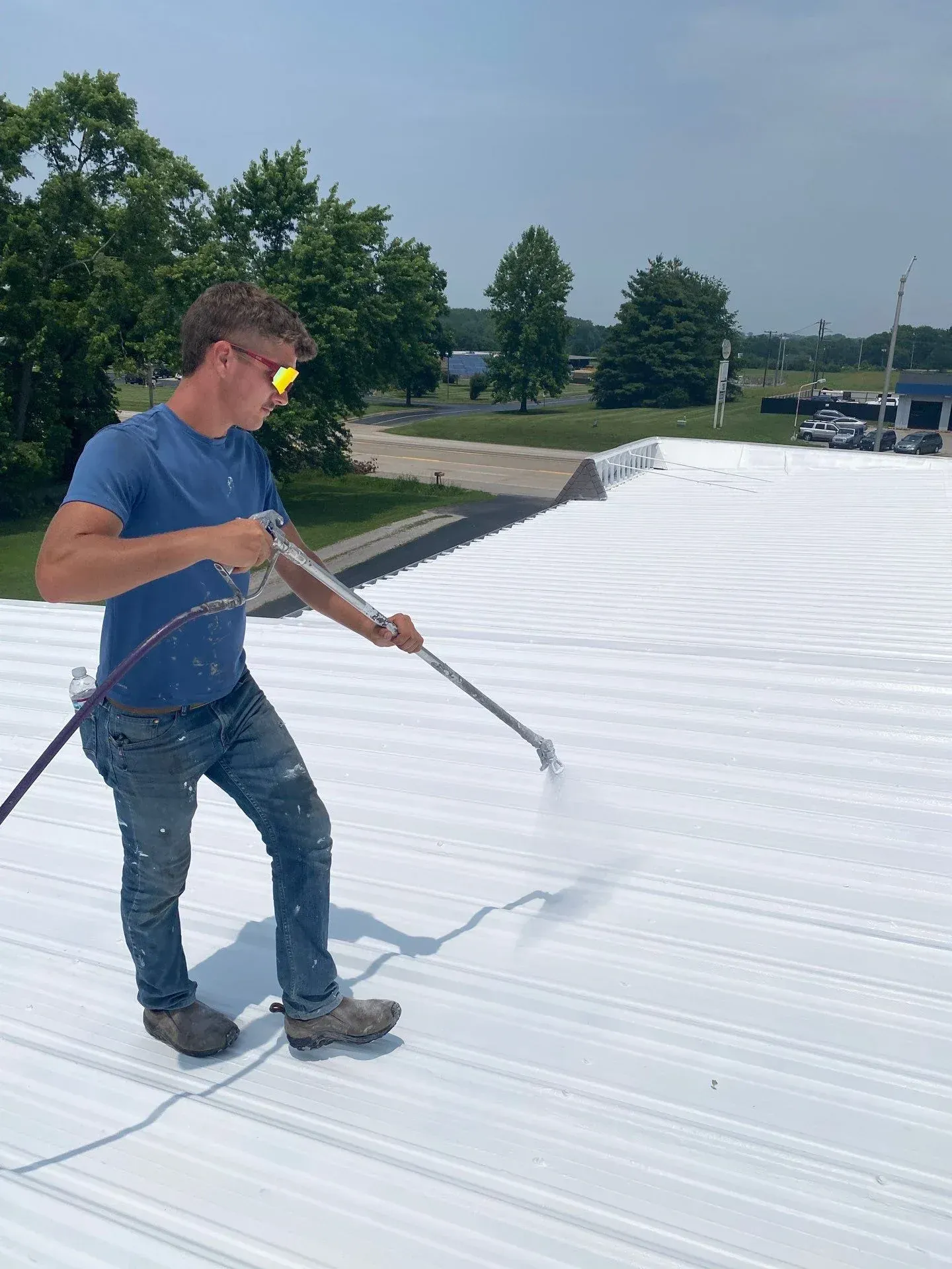 Commercial roofer applying a white reflective coating to a metal roof