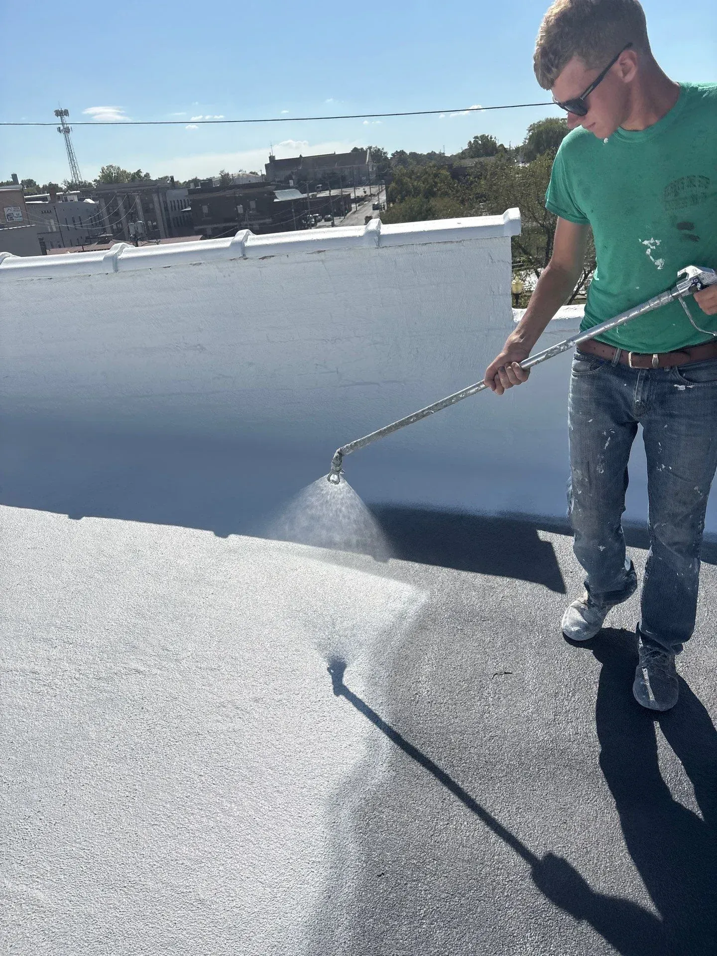 Commercial roofer spraying a protective roof coating onto a flat commercial roof