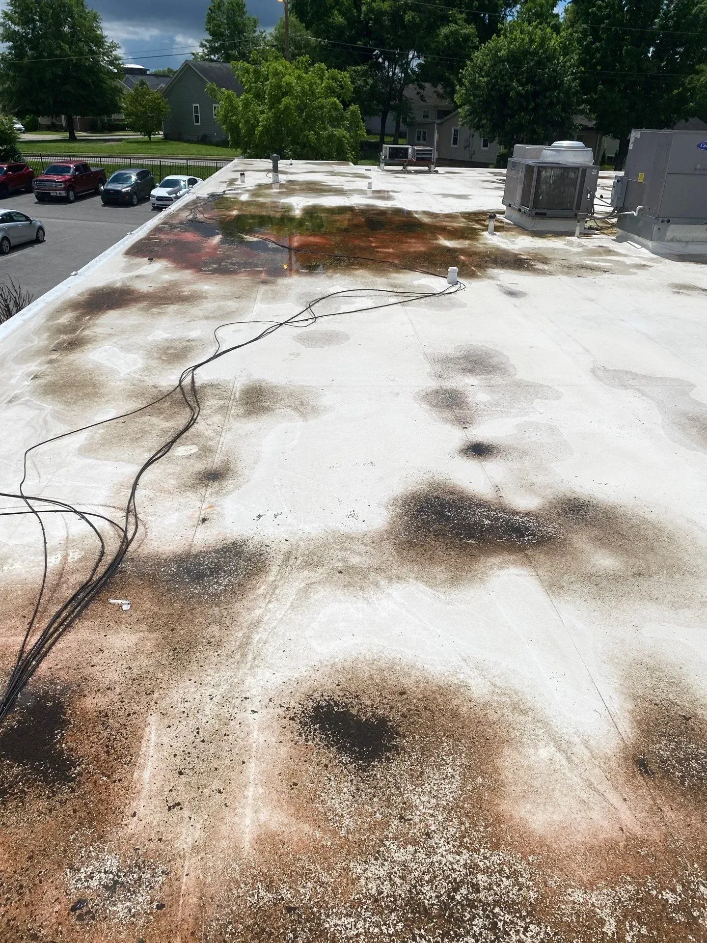 Commercial flat roof membrane with visible ponding water and staining before repair