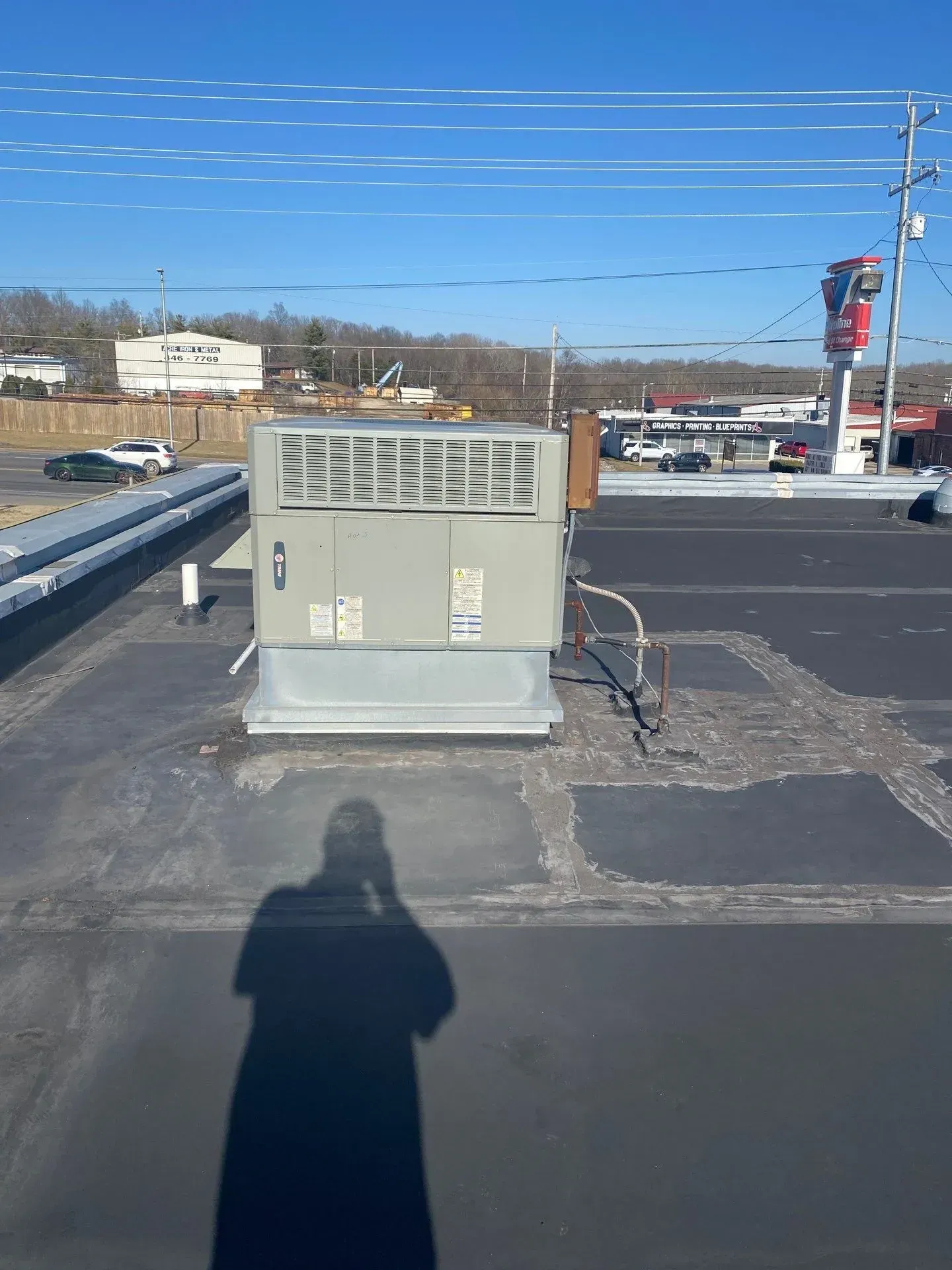 Repaired sections of a commercial flat roof around an HVAC unit