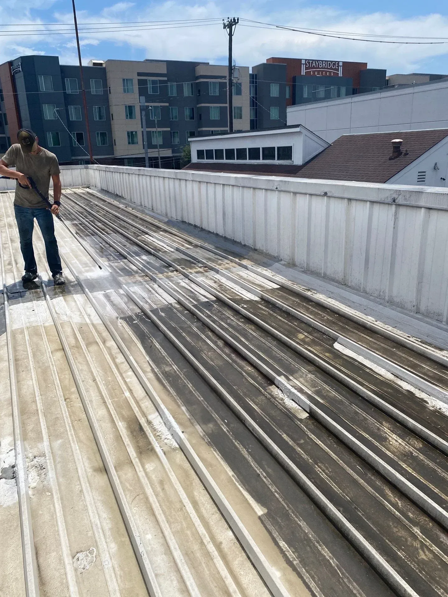 Technician pressure washing metal roof surface to prepare for coating in Nashville, Tennessee