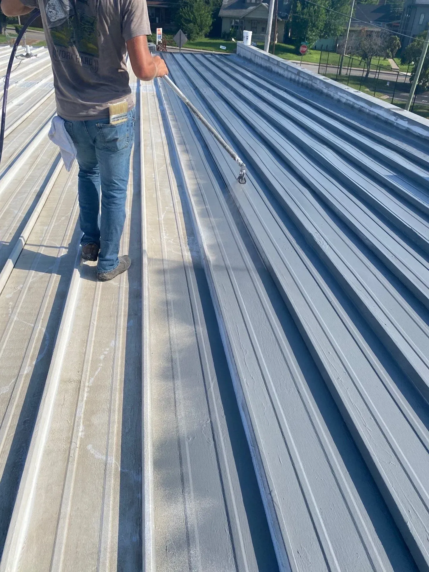 Technician applying reflective roof coating to a commercial metal roof in Nashville, Tennessee
