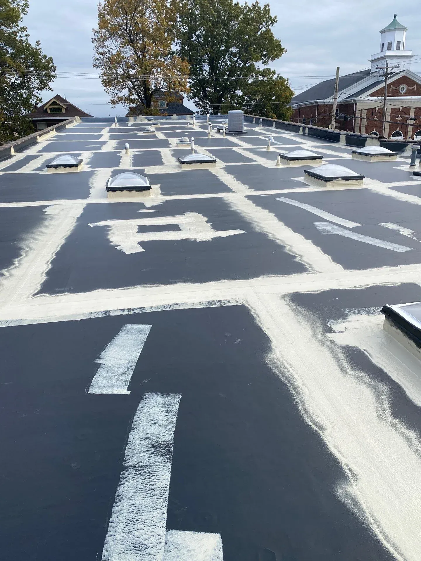 Commercial roof seam repair and base coat application during restoration in Paducah, Kentucky