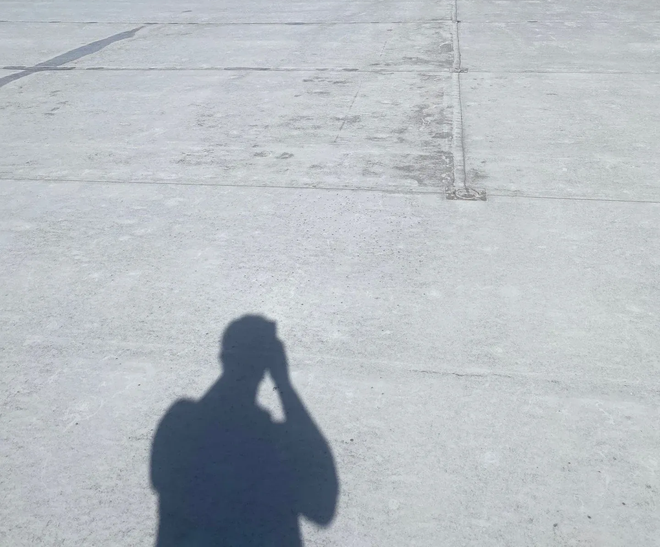 Roofing technician conducting a condition survey walkthrough of a large commercial flat roof
