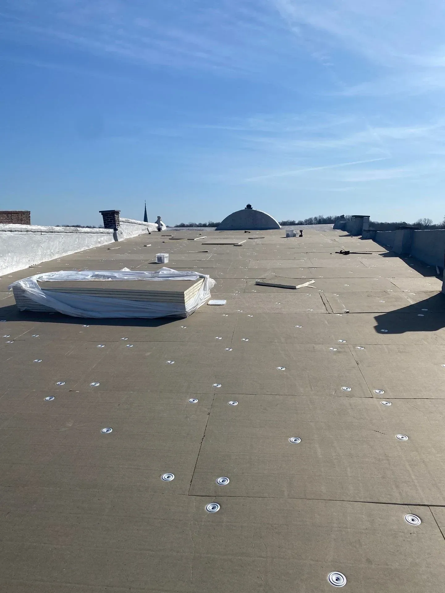 New insulation board being installed during a commercial roof replacement