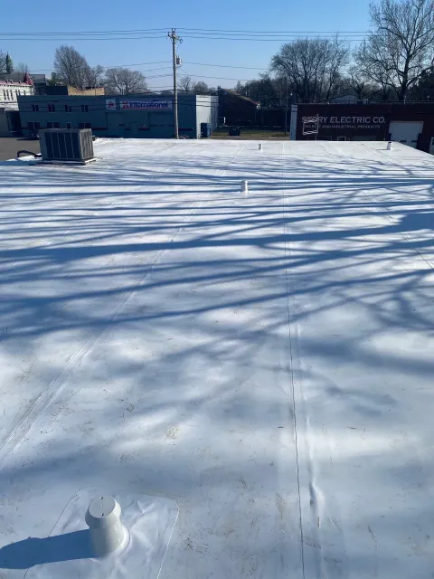 Completed single-ply membrane roof showing seam pattern and prefabricated pipe boot detail