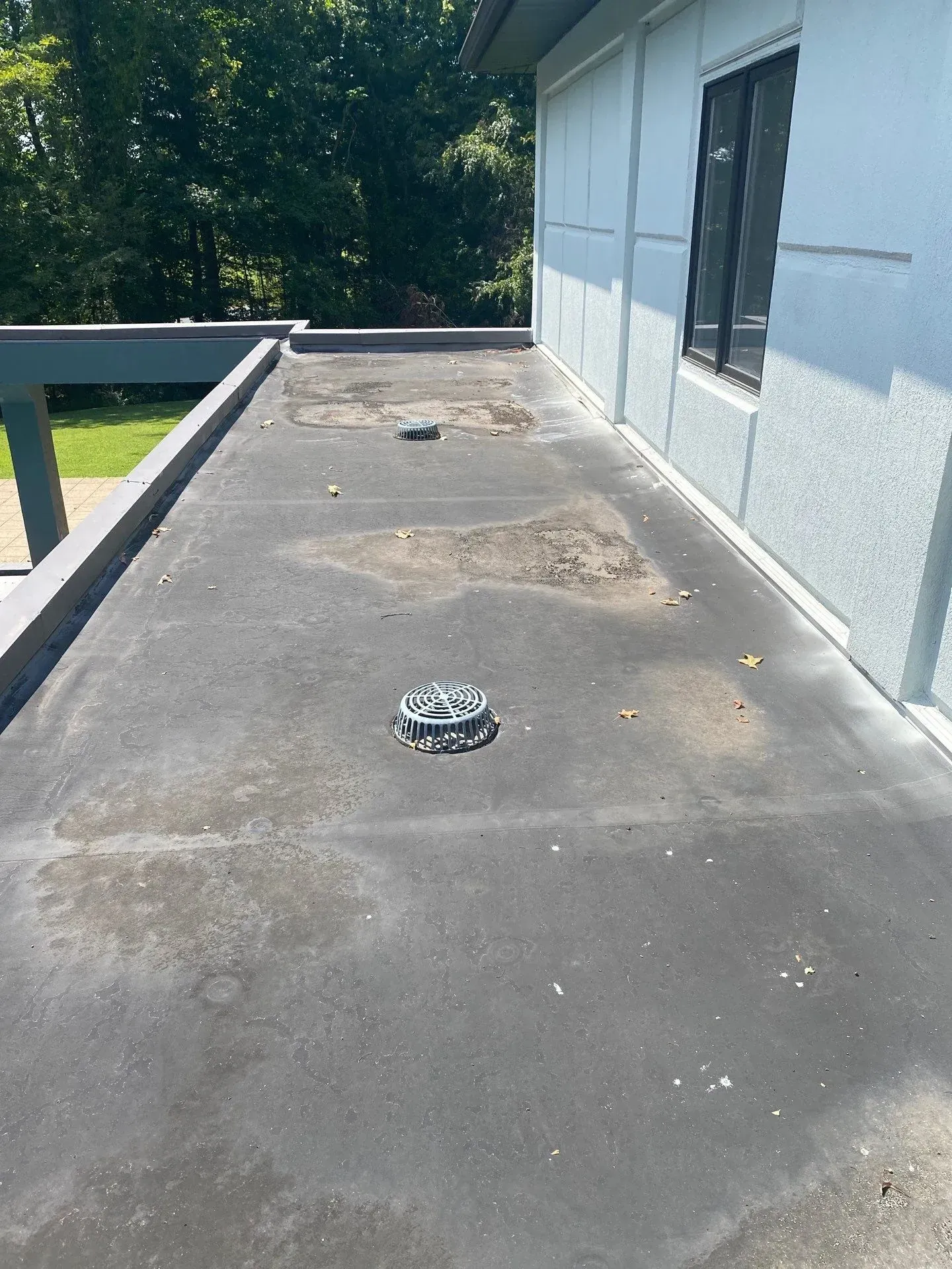 Aged dark single-ply membrane roof section before recoating on a residential flat roof in Tell City, Indiana
