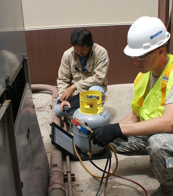 A man wearing a hard hat is working on a propane tank