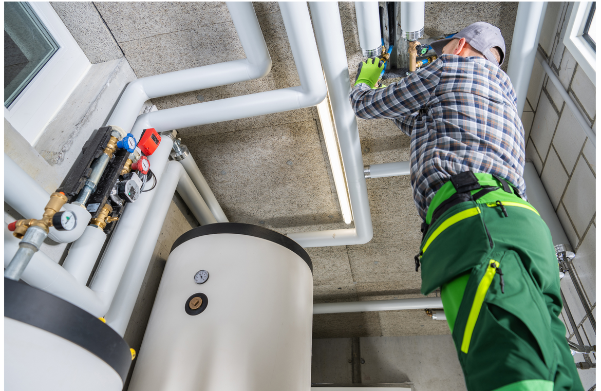 A man is working on pipes in a building.