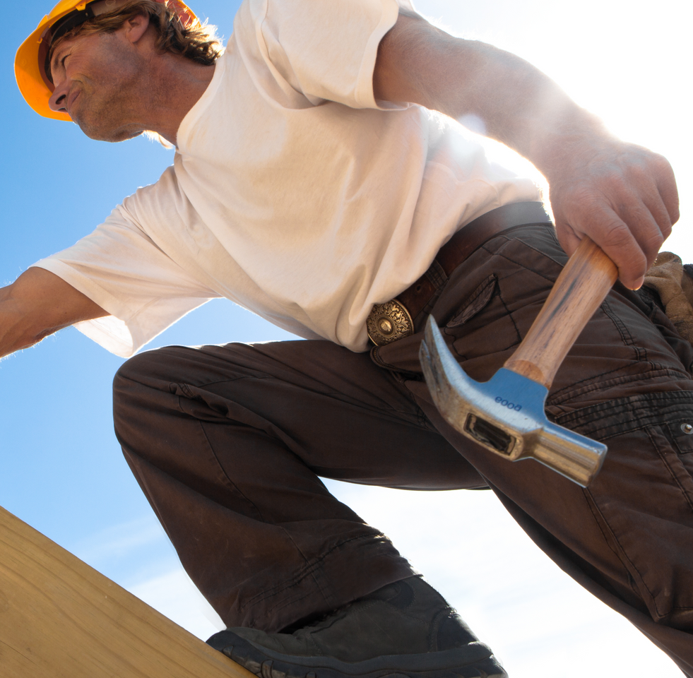 A man wearing a hard hat is holding a hammer