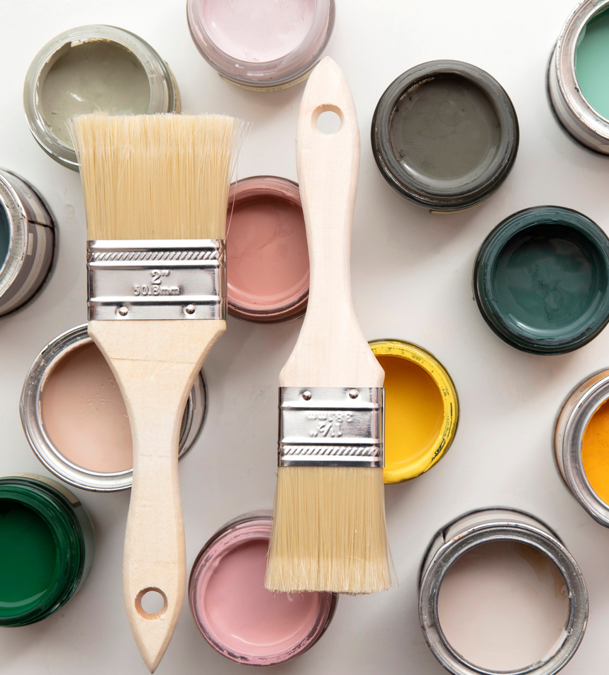 Two paint brushes are surrounded by cans of paint of different colors