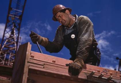 A man wearing a hard hat is working on a piece of metal