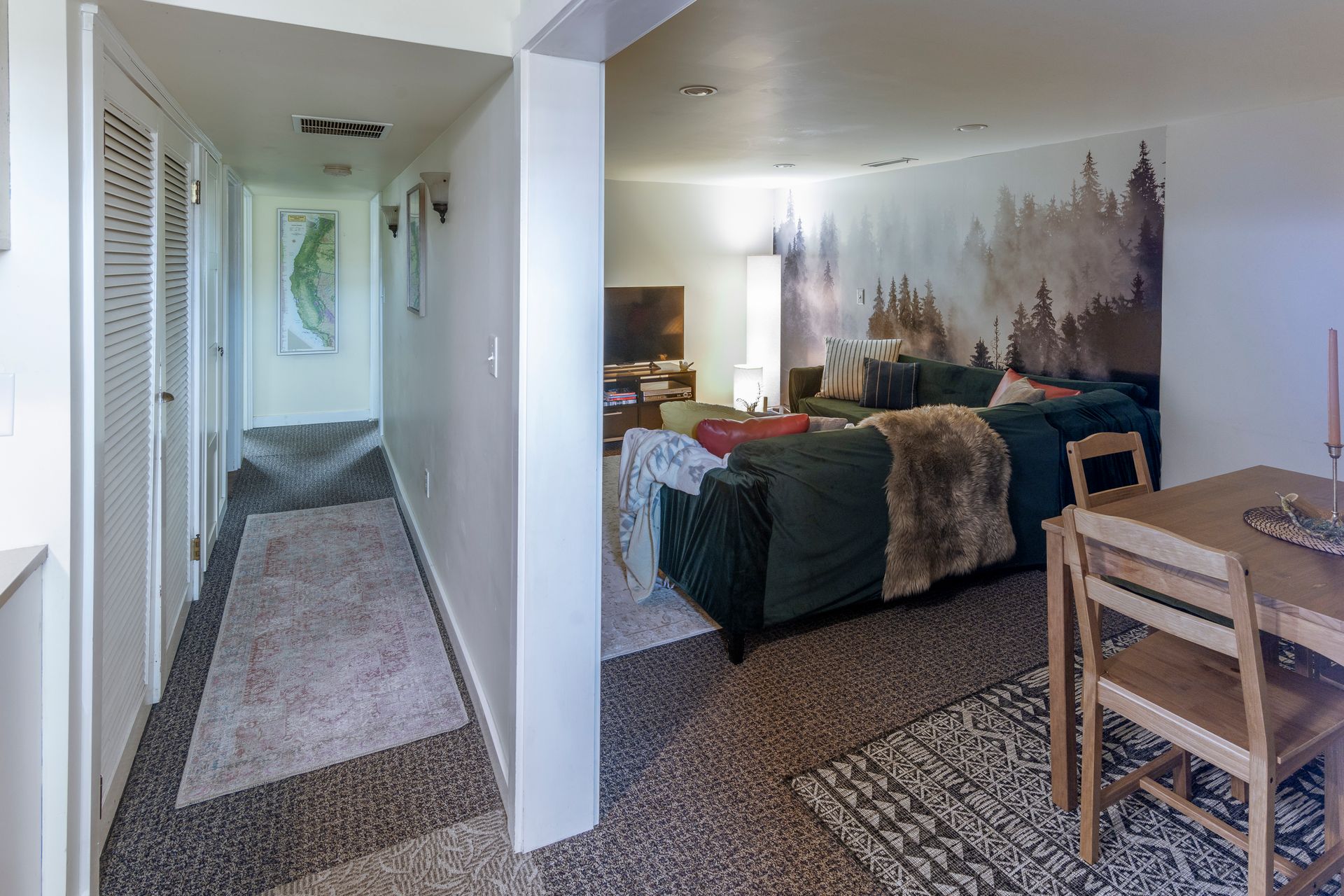 Apartment interior with hallway, bedroom, bed, desk, and patterned carpet in soft neutral tones
