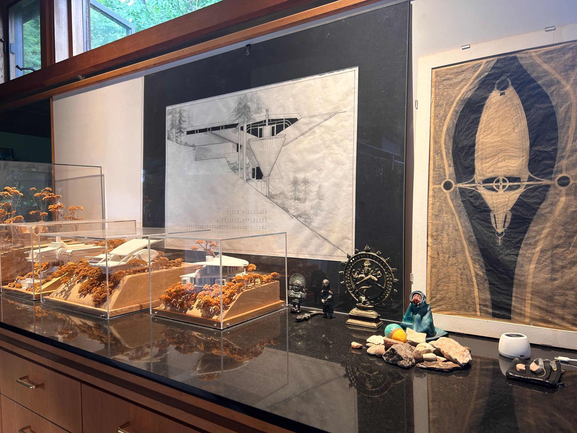 Display case with art prints, model builds, and small figurines in a gallery or museum setting