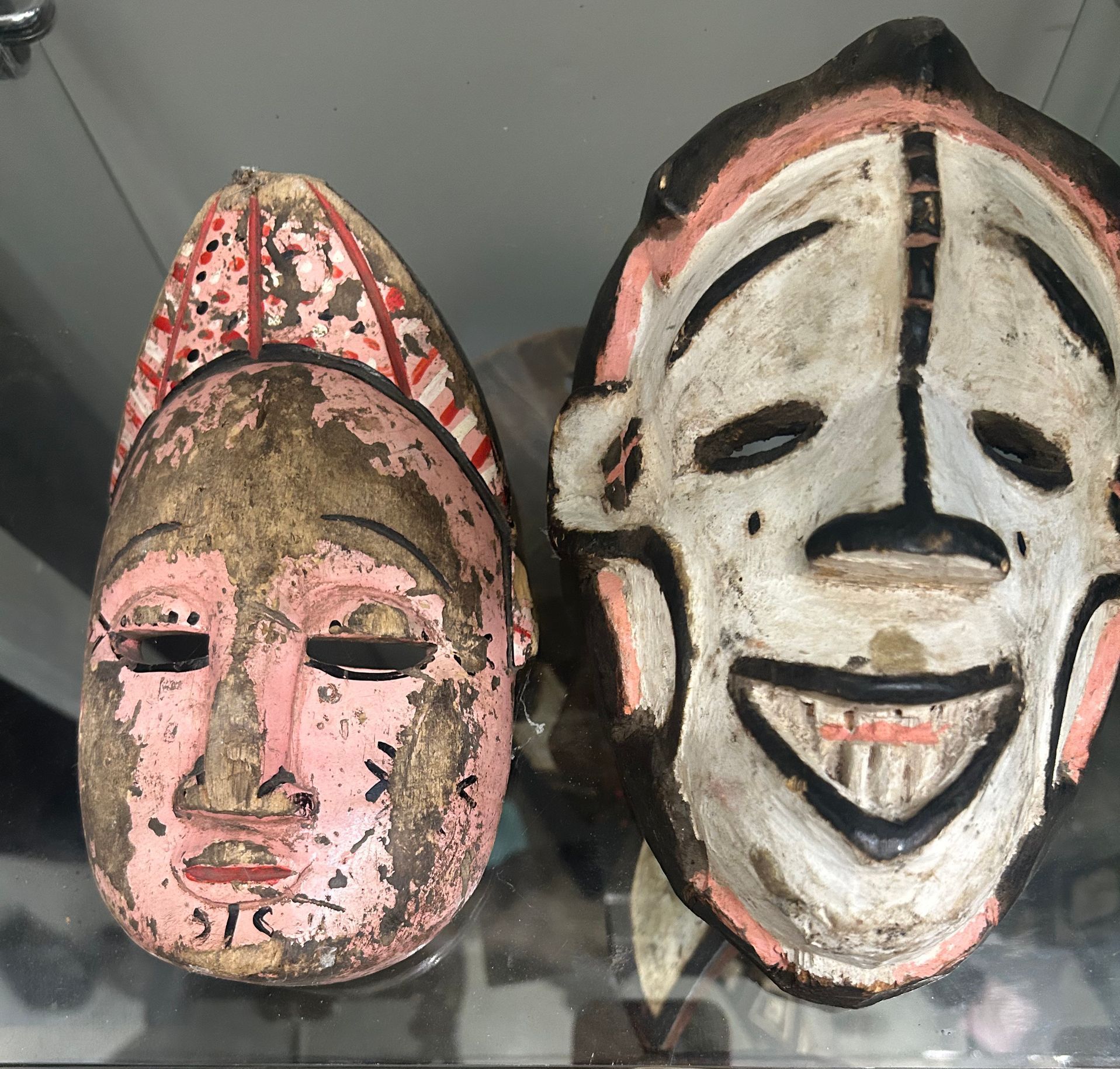 Two decorative carved masks, one pink and one white, displayed side by side.