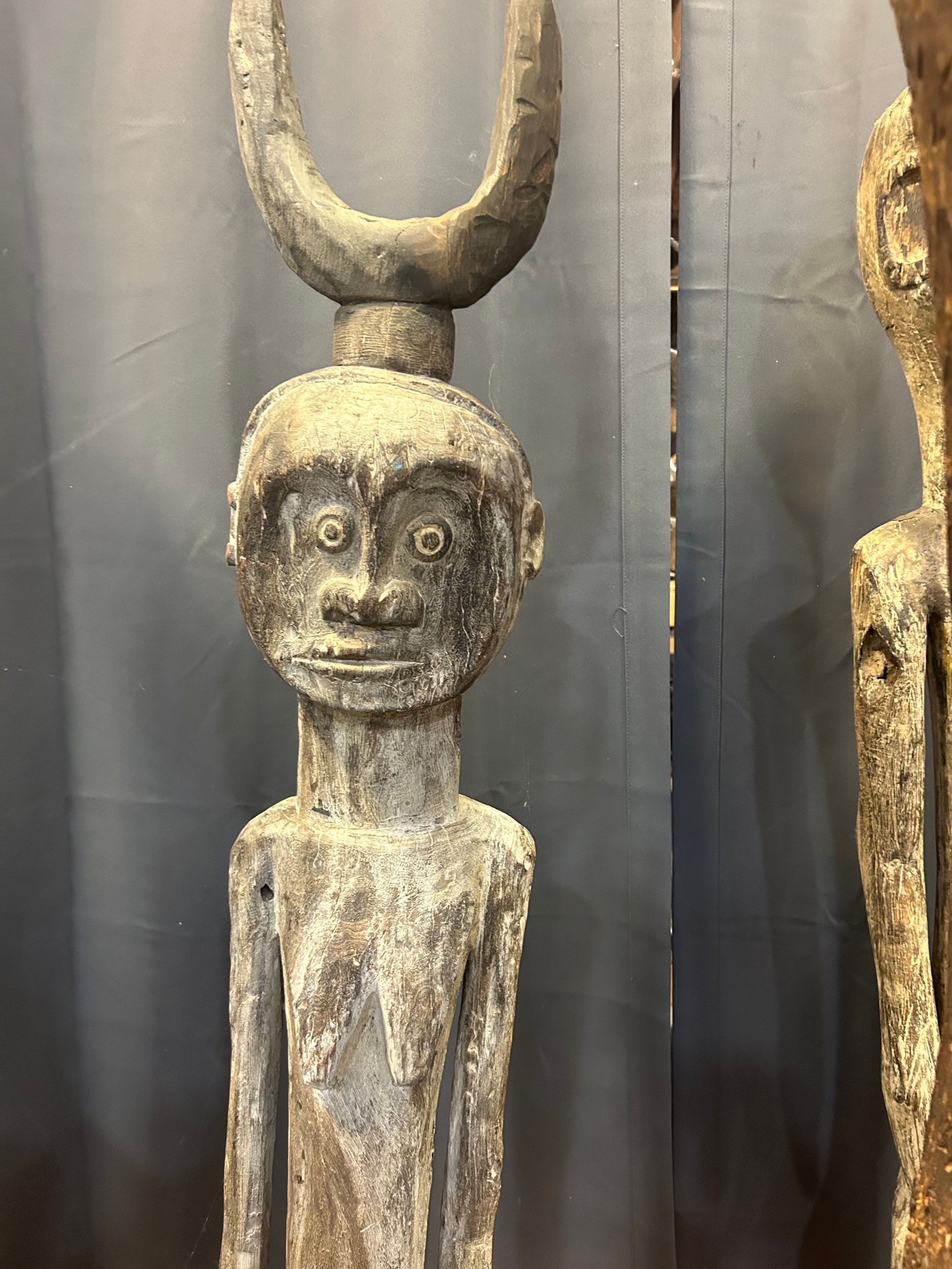 Ancient wooden statue with a horned headpiece displayed in a museum exhibit