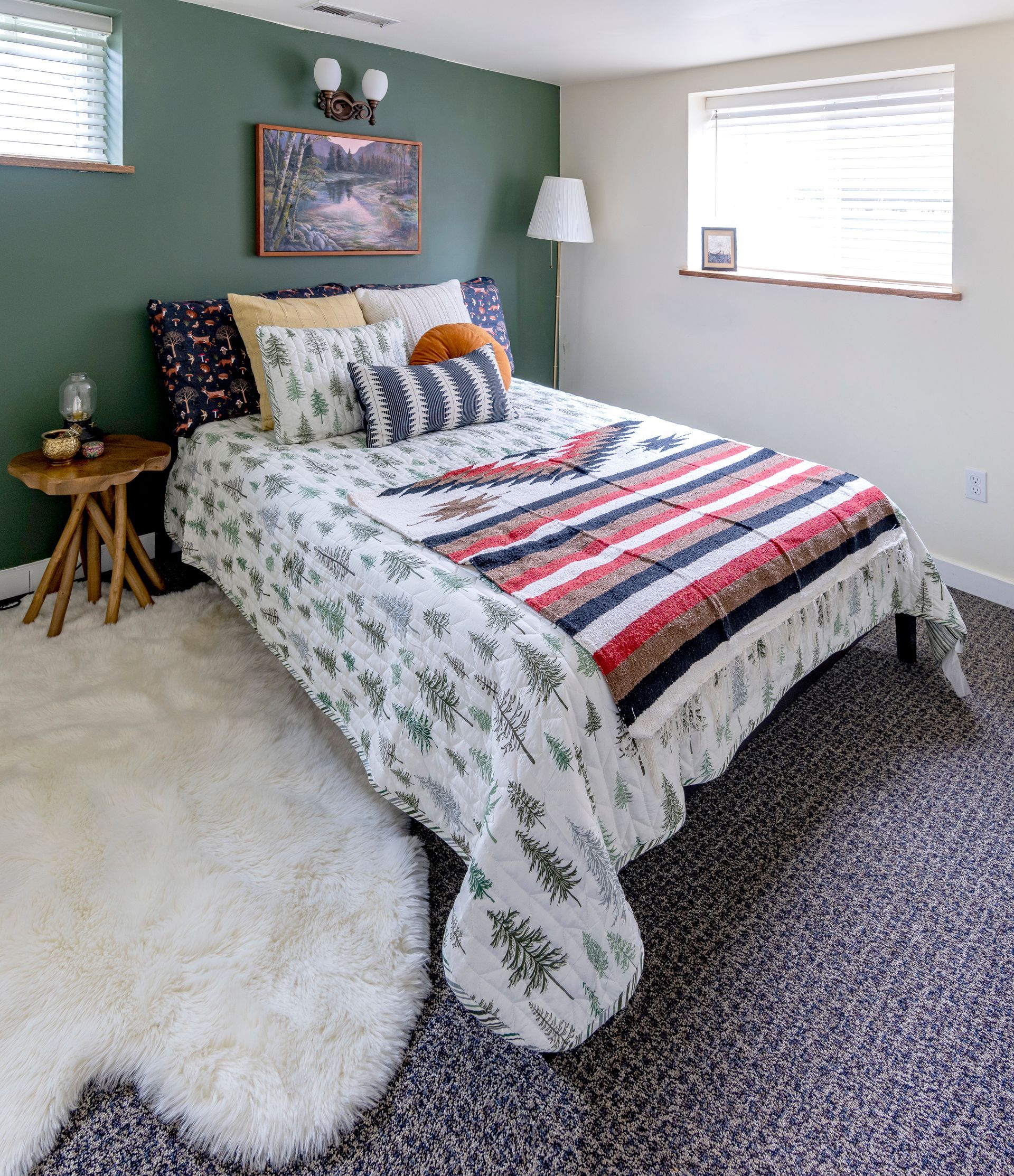 Cozy bedroom with a patterned bedspread, green accent wall, shag rug, and window light