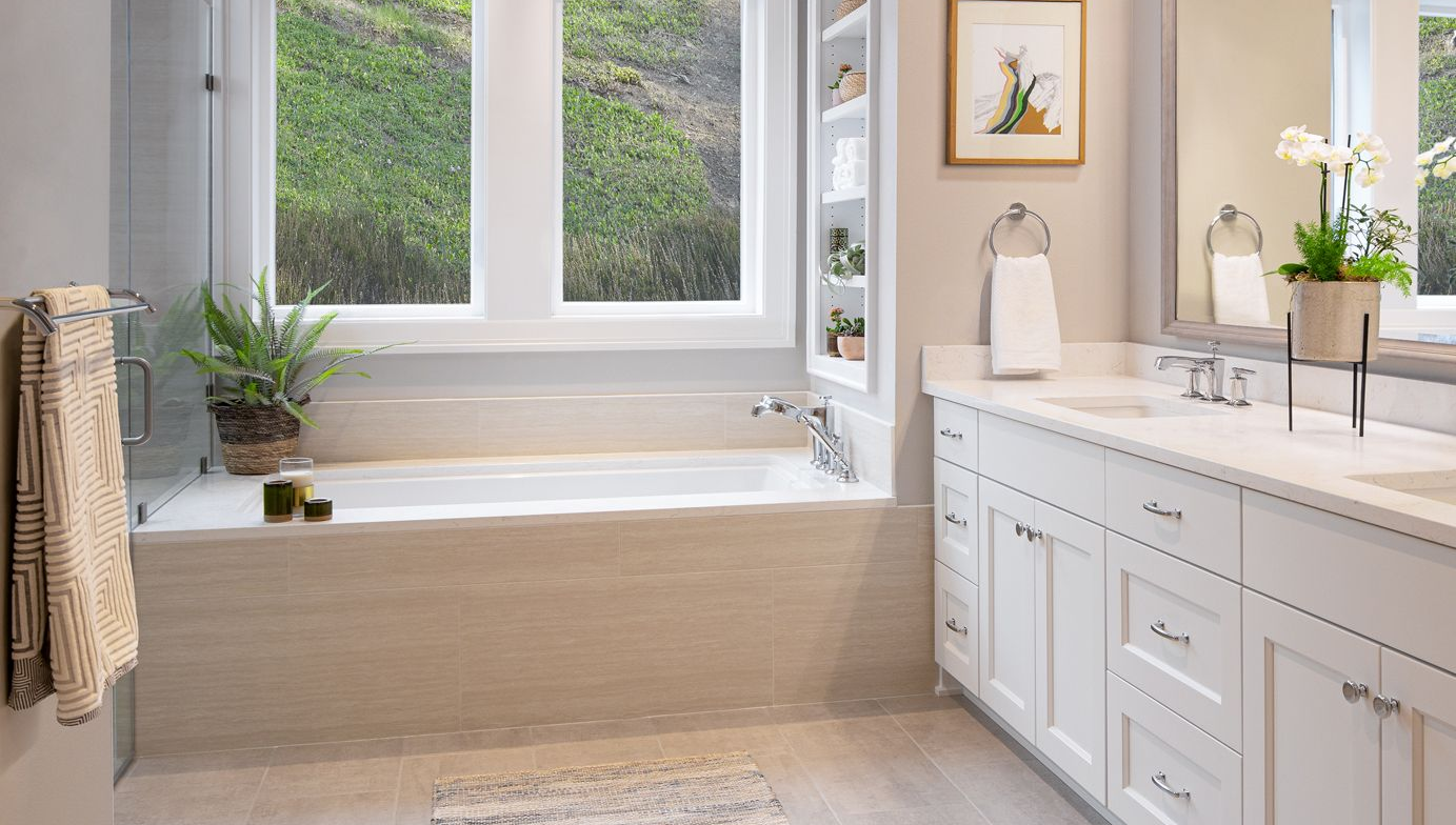 Bright modern bathroom with a large window, soaking tub, and white vanity with a potted plant