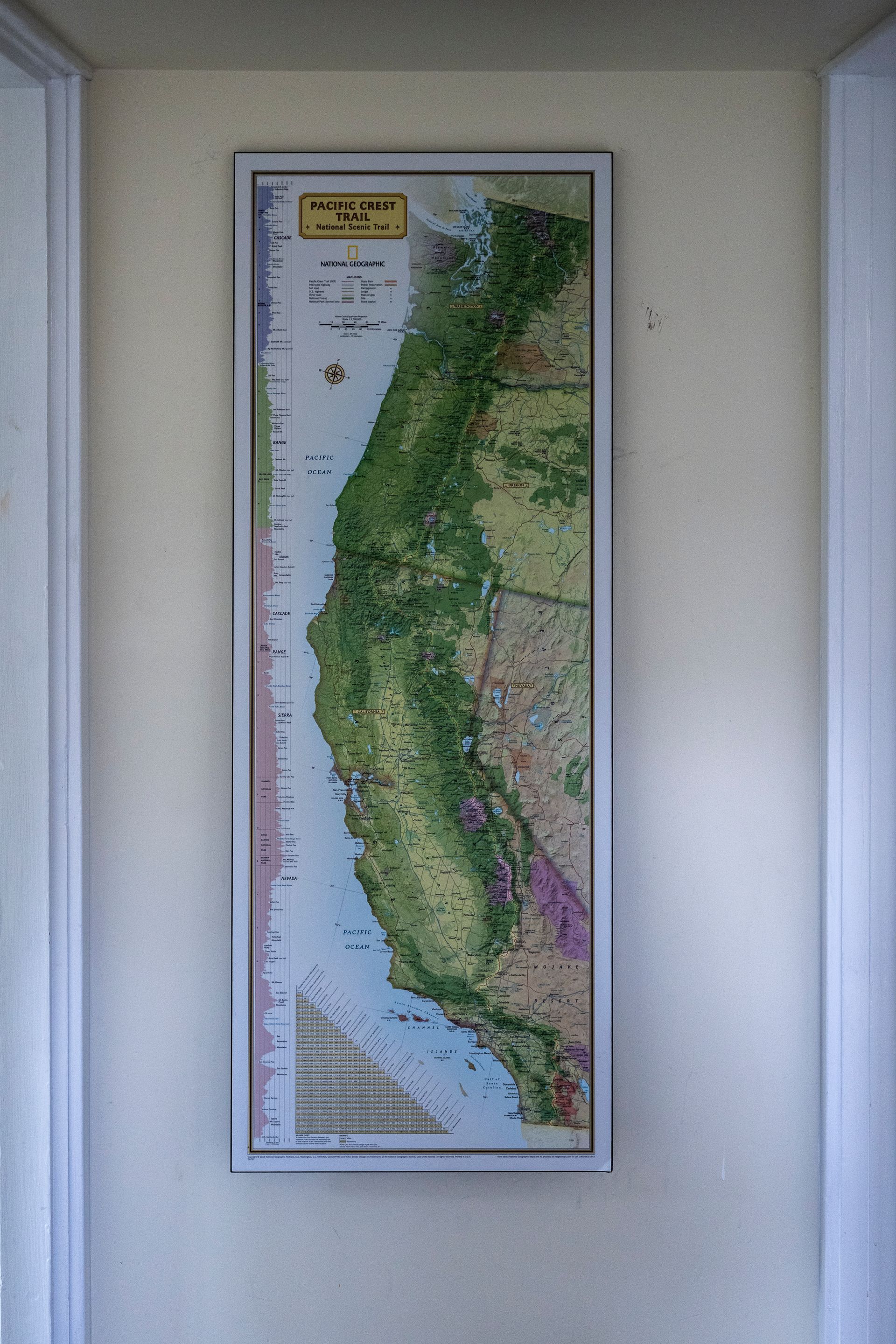 Framed map of coastal Chile on a wall, showing green land and ocean along a narrow vertical strip