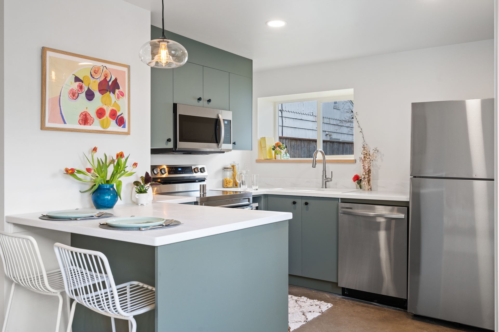 Bright modern kitchen with white island, gray cabinets, stainless appliances, and blue accents