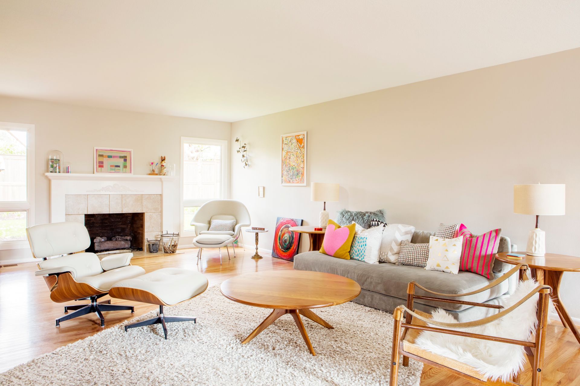 Bright living room with fireplace, sofa, wooden chairs, round coffee table, and colorful pillows