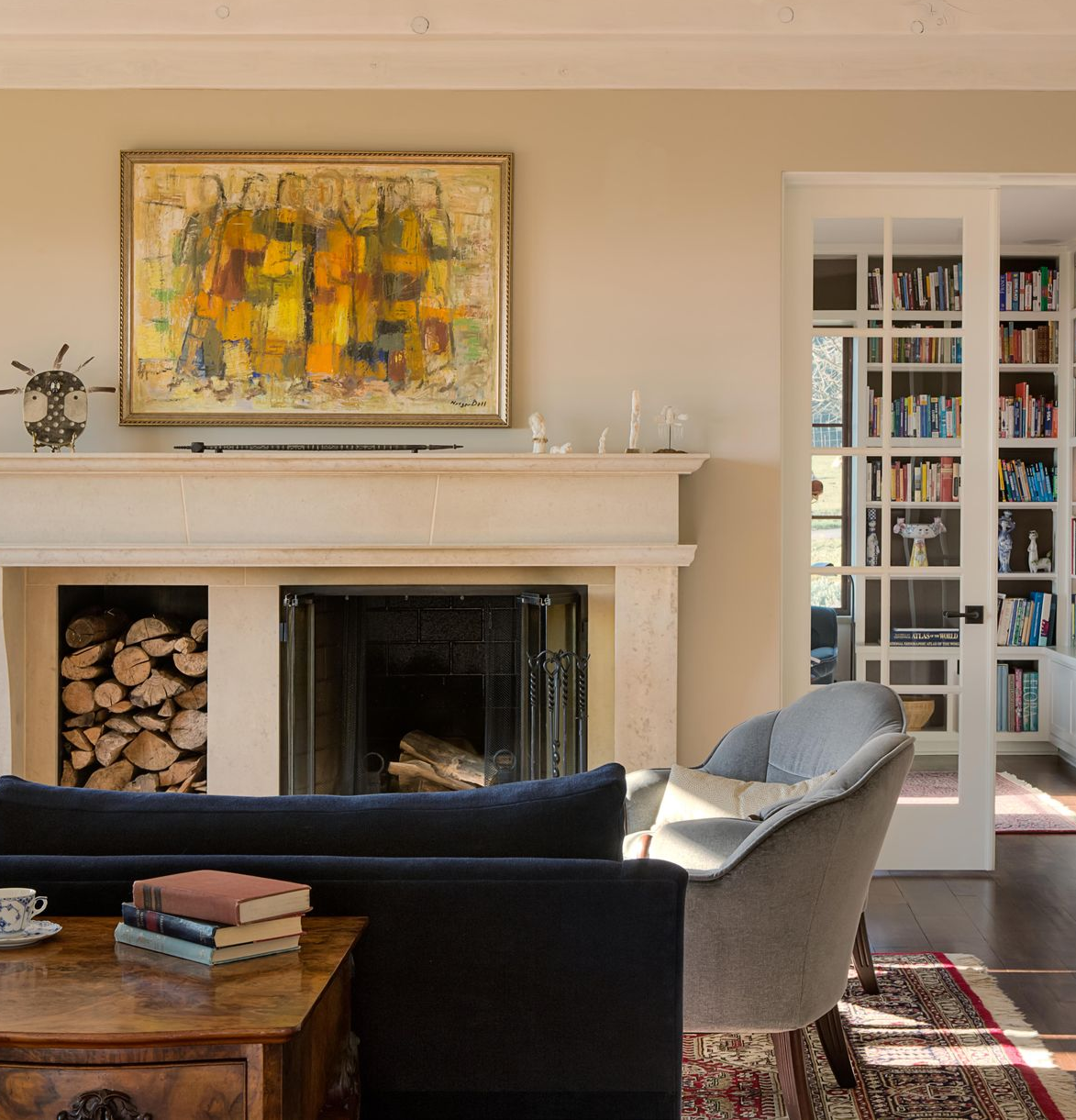 Cozy living room with fireplace, abstract art, bookshelves, and sunlight through French doors