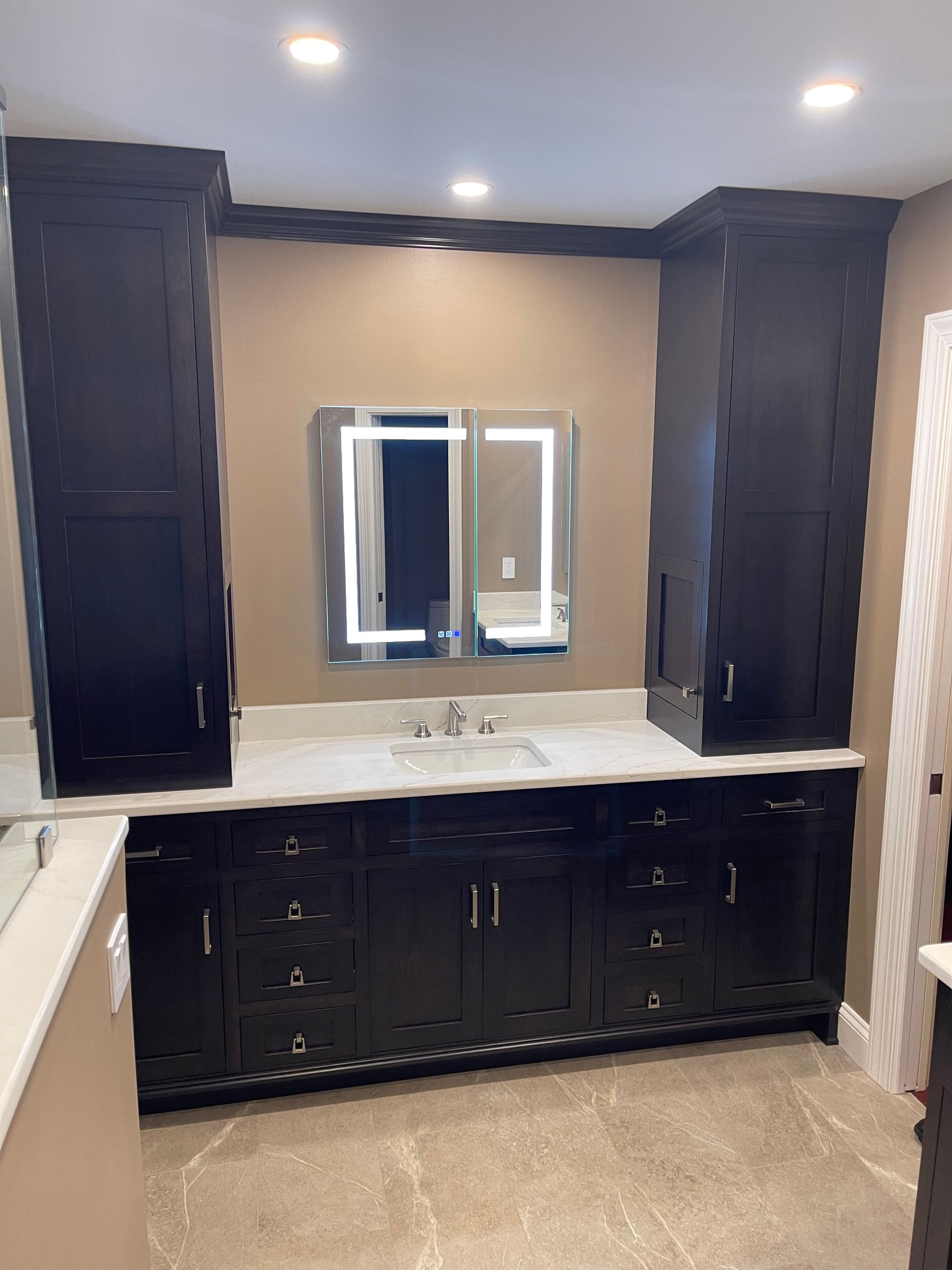 A bathroom with black cabinets , a sink and a mirror.