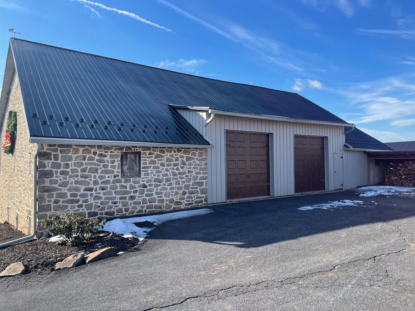 A stone building with a metal roof and two garage doors.