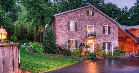 A large brick house with a driveway in front of it and trees in the background.