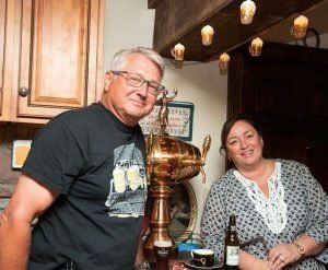 A man and a woman are standing in front of a beer tap