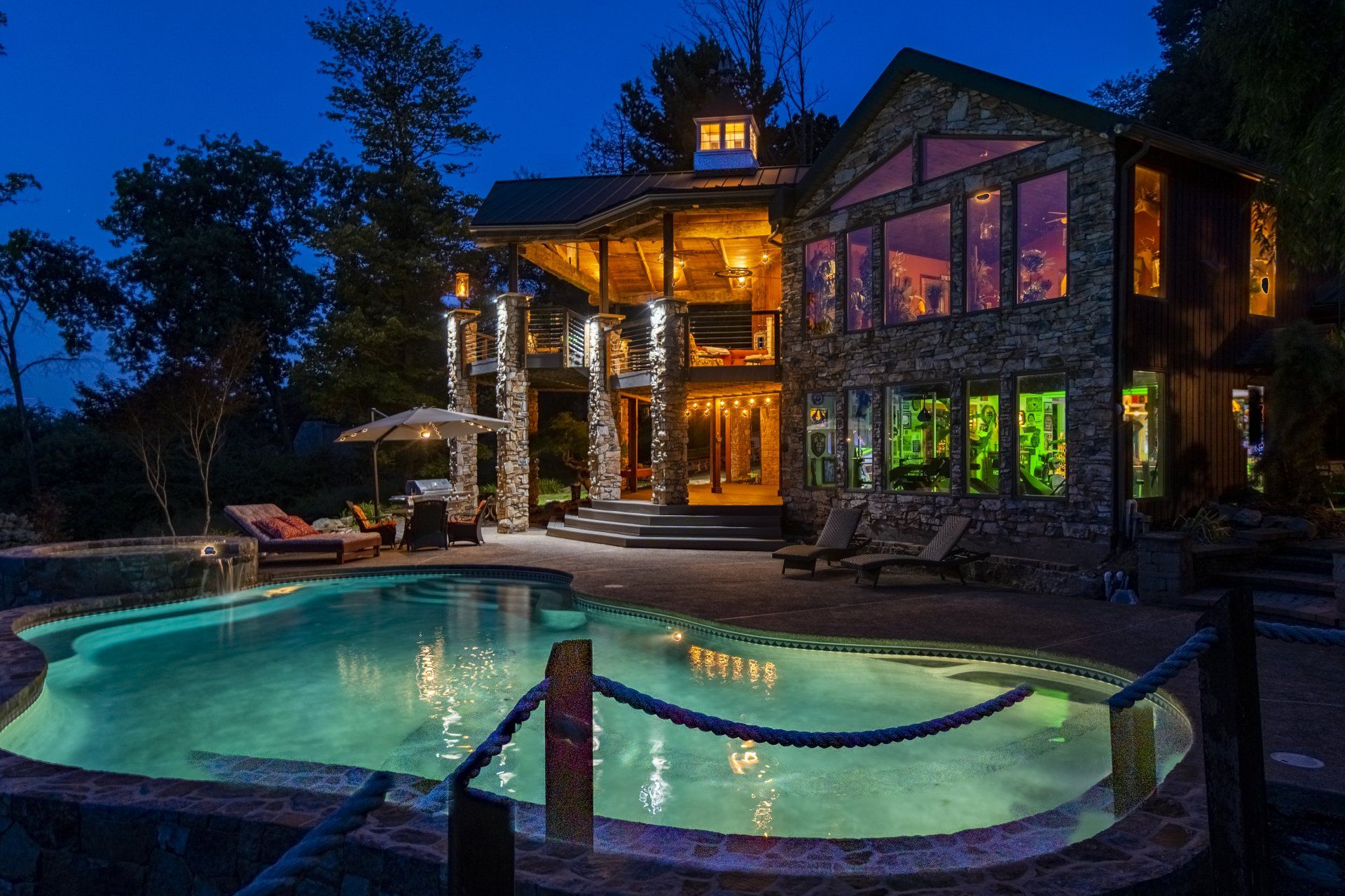 A large house with a swimming pool in front of it at night