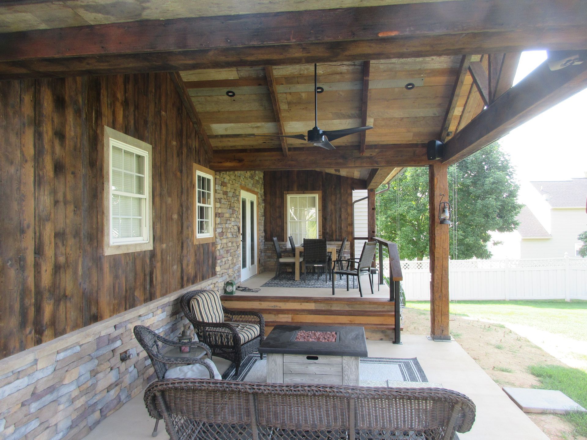 A porch with a couch , chairs , and a ceiling fan.