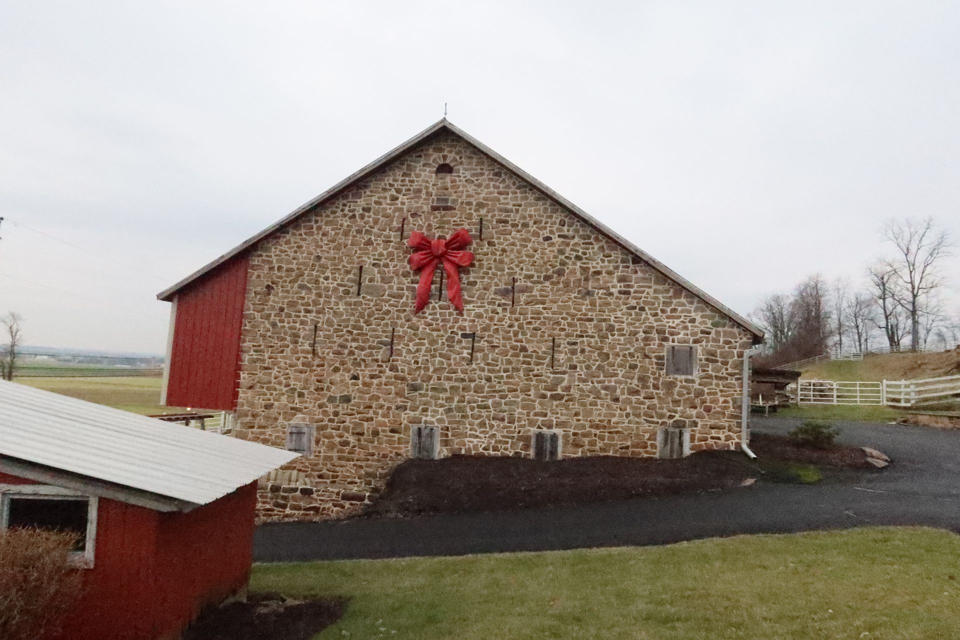 A large stone barn with a red bow on the side.