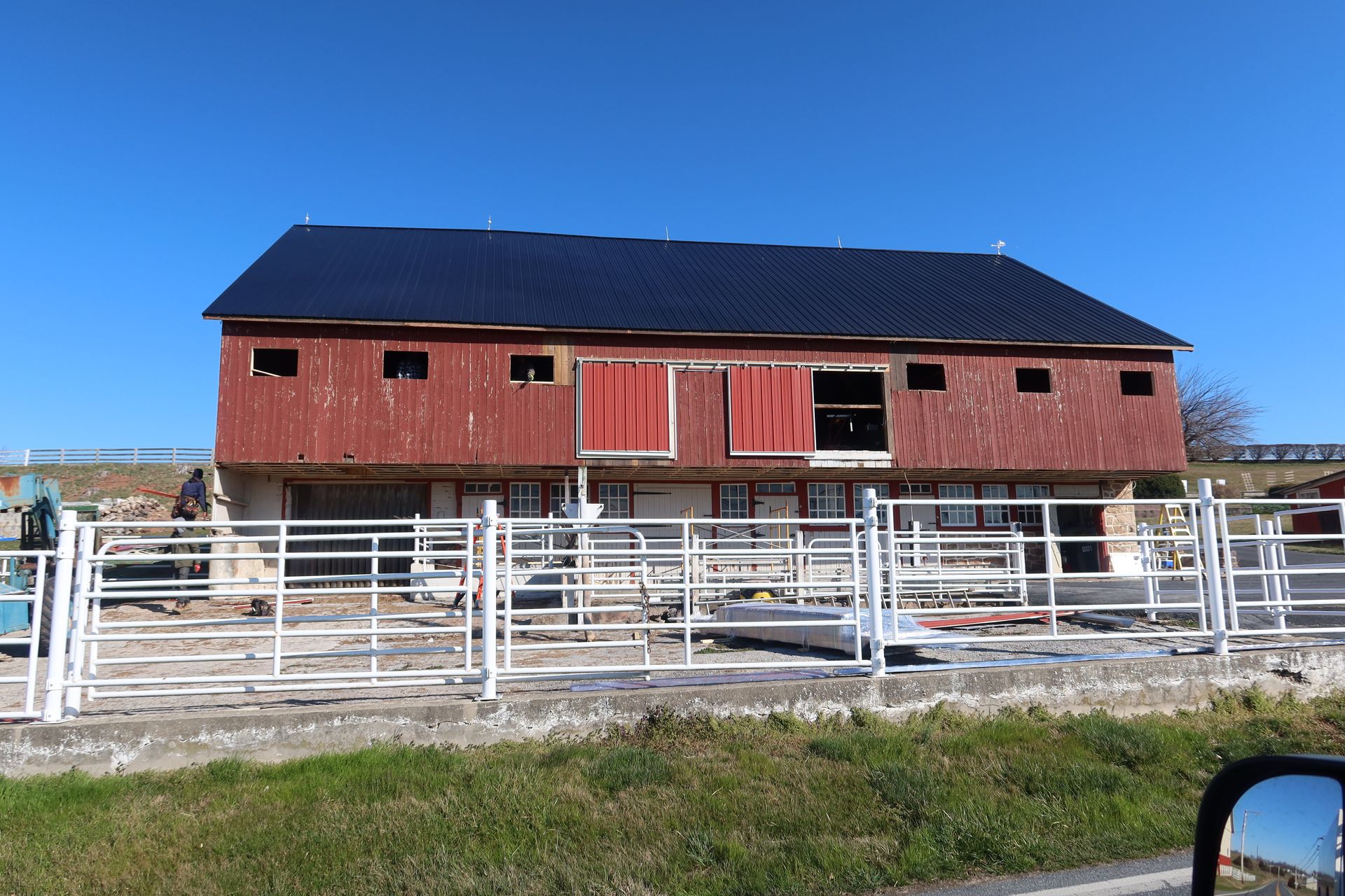 A red barn with a black roof is being built on a farm.