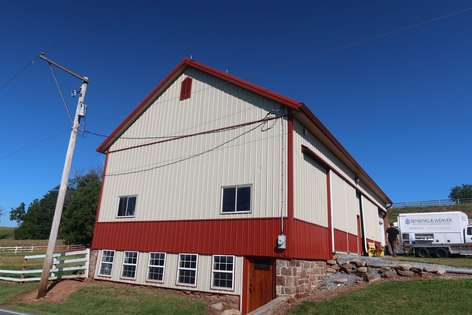 A red and white barn is sitting in the middle of a grassy field.