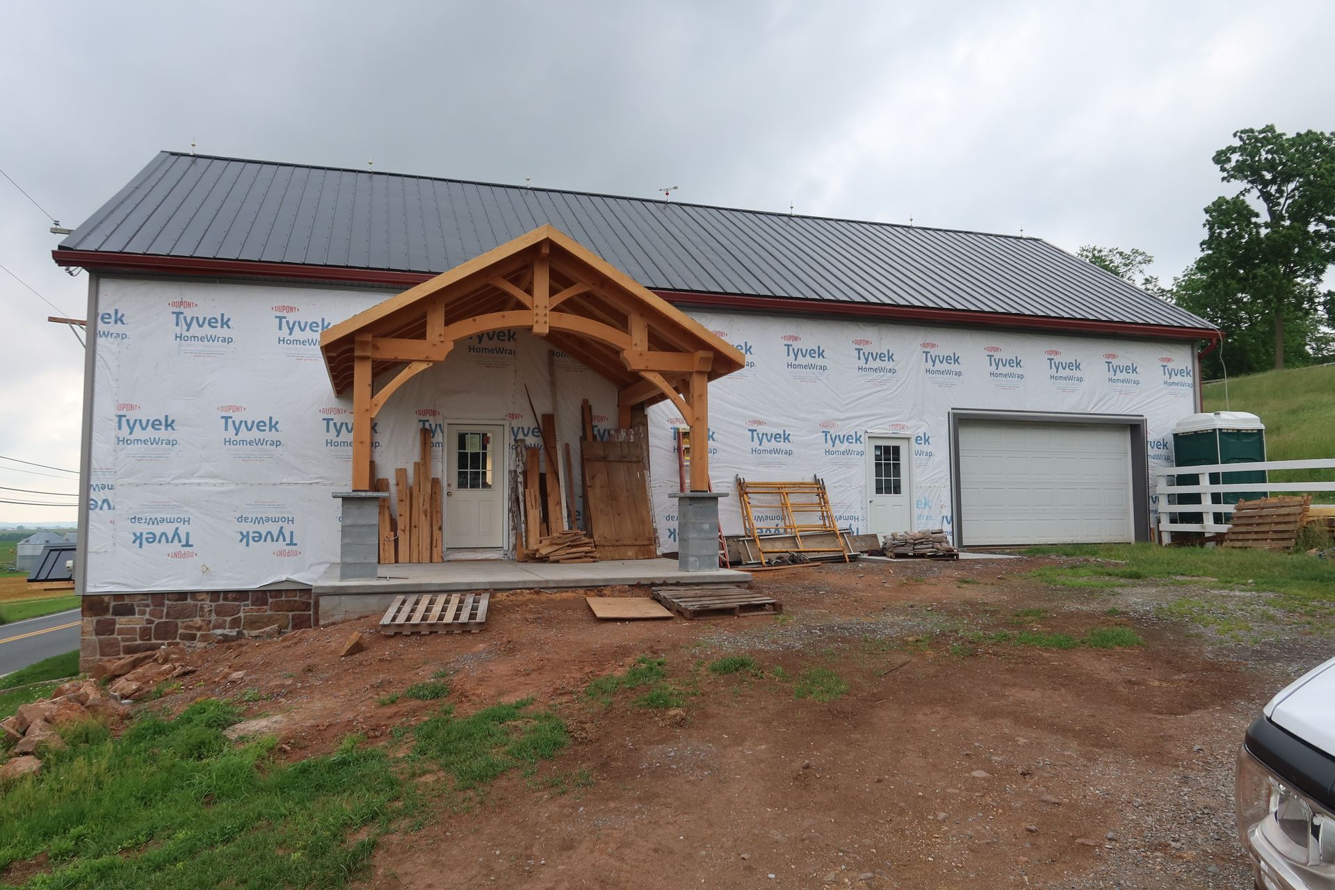 A house is being built with a wooden porch and a metal roof.