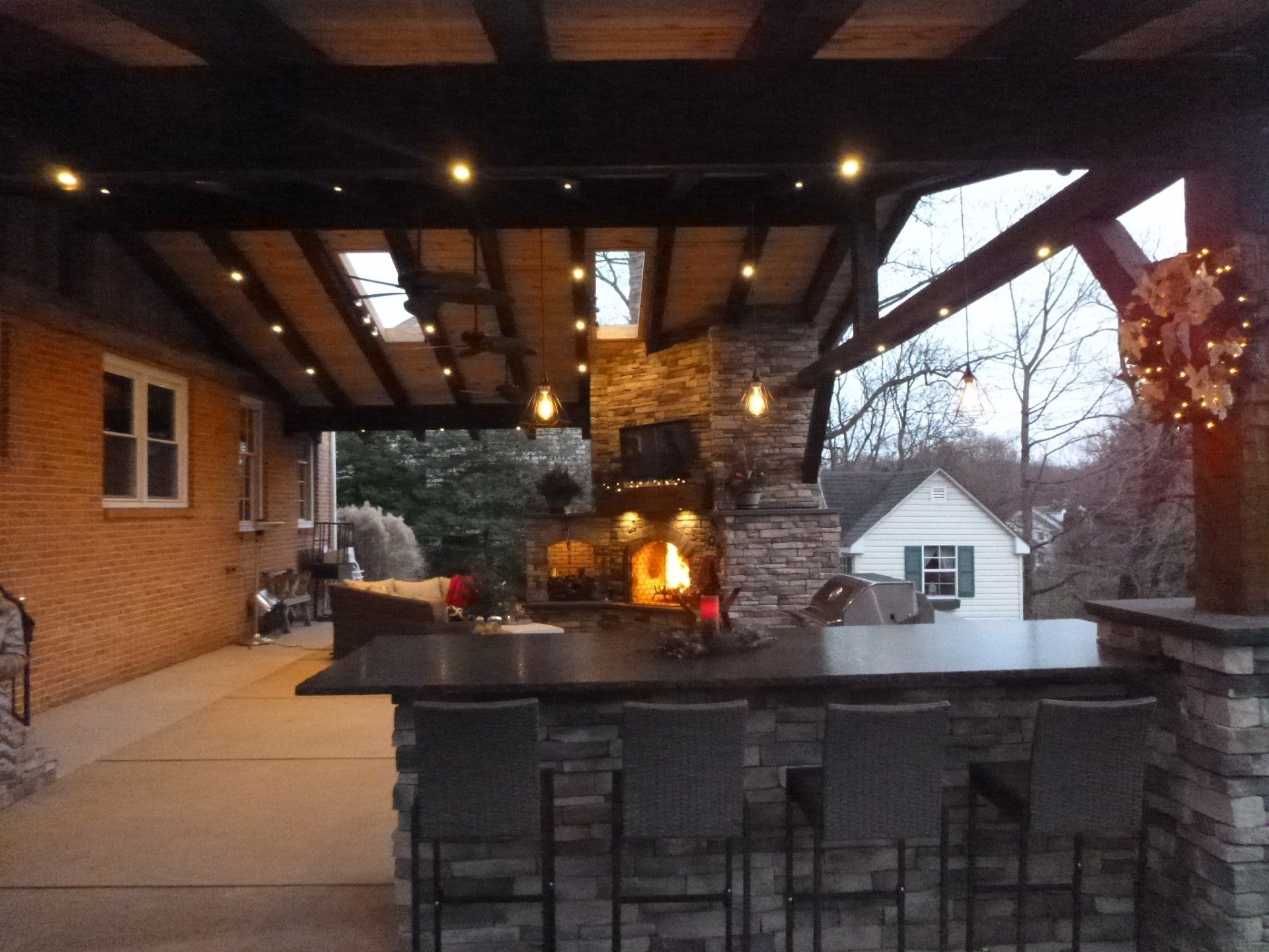 A covered patio with a fireplace and a bar
