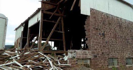 A brick building with a white roof is being demolished.