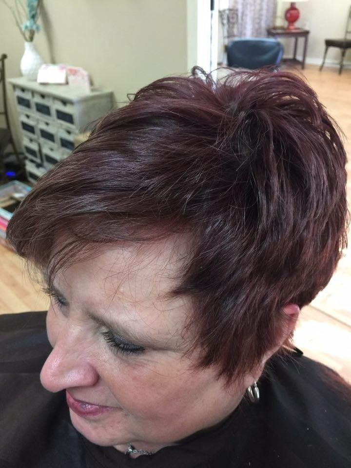Woman with short burgundy hair looking down in an indoor room