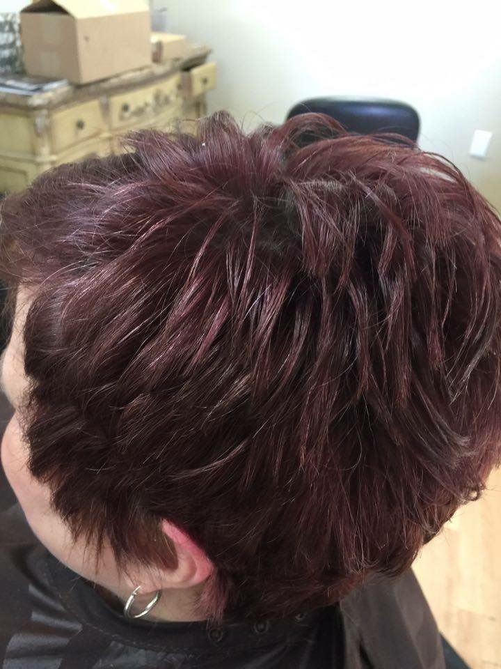 Close-up of a short, tousled burgundy hairstyle in a room with boxes in the background